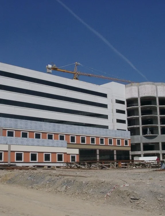 Cephe kaplaması süren çok katlı yapı ve otopark bloğu